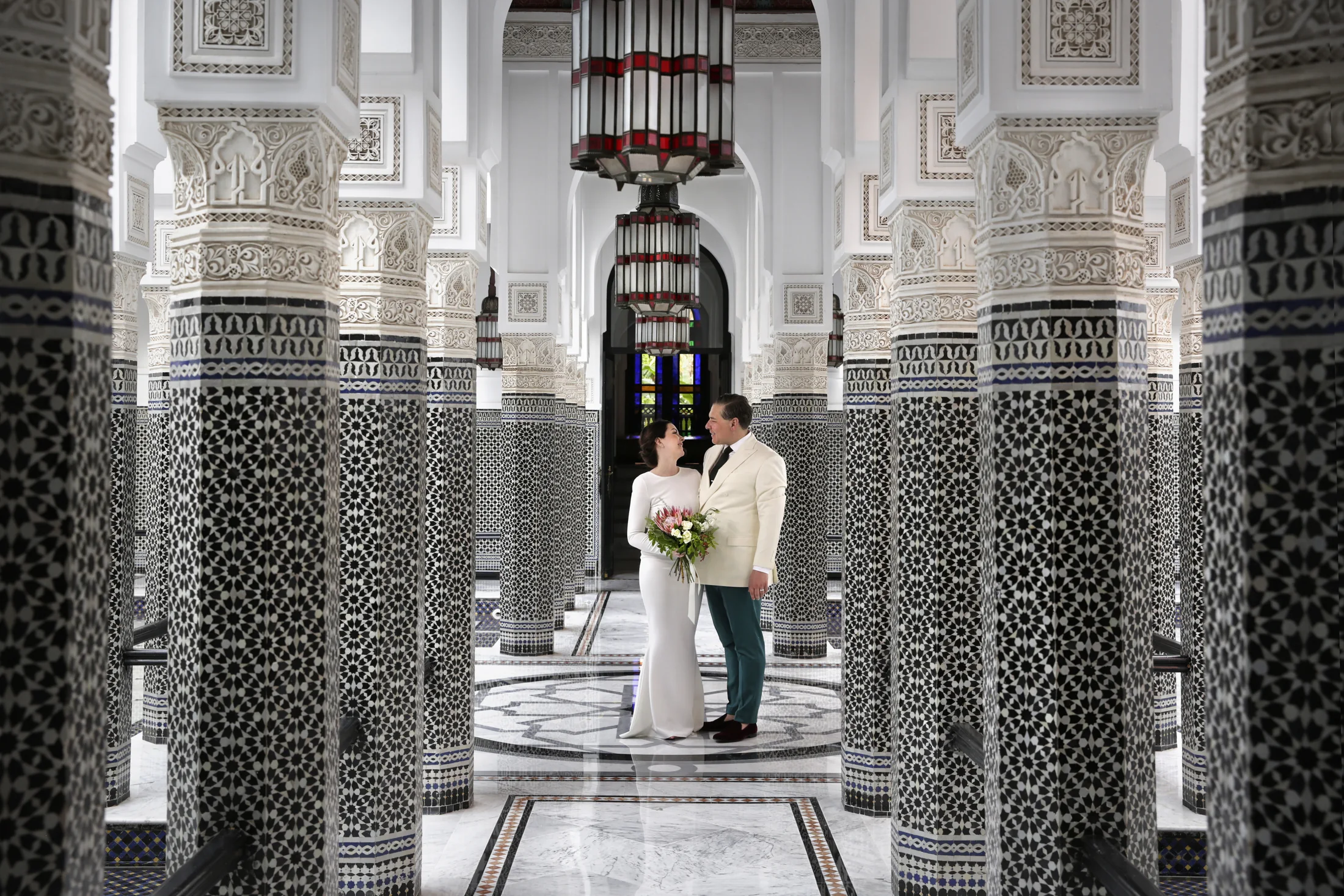 A newlywed couple framed by the patterned columns of a Marrakech interior
